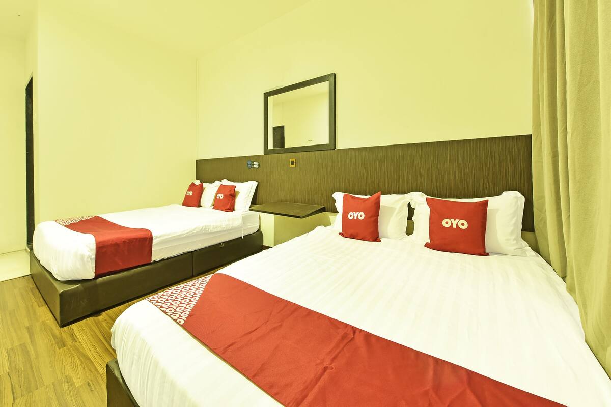 Habitación de hotel con dos camas, cada una con ropa de cama y almohadas rojas y blancas con la etiqueta “OYO”.
