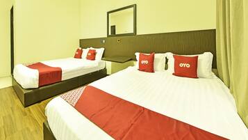 Quarto de hotel com duas camas, cada uma com roupa de cama e almofadas vermelhas e brancas com a etiqueta "OYO".