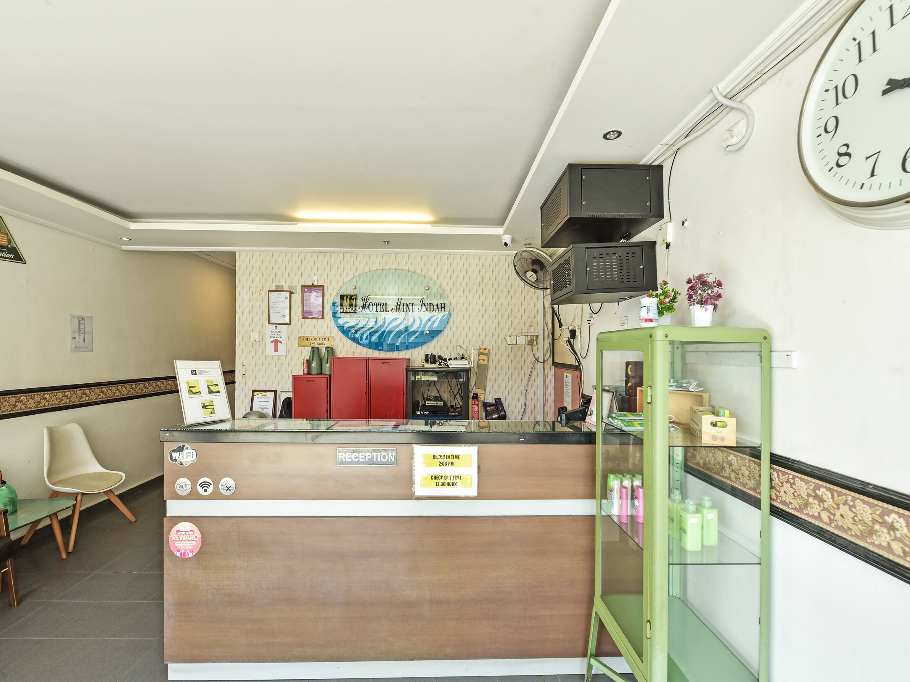 A hotel reception area with a reception desk, a clock, and a reception sign.