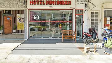 Entrada de um hotel com uma placa indicando "HOTEL MININDAH" e um preço de "RM 50 POR NOITE".