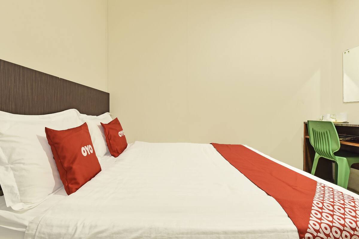 Habitación de hotel con cama, escritorio y una silla verde.