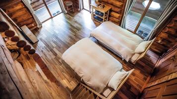 A cabin with two beds, wooden floors, a small table, and a window.