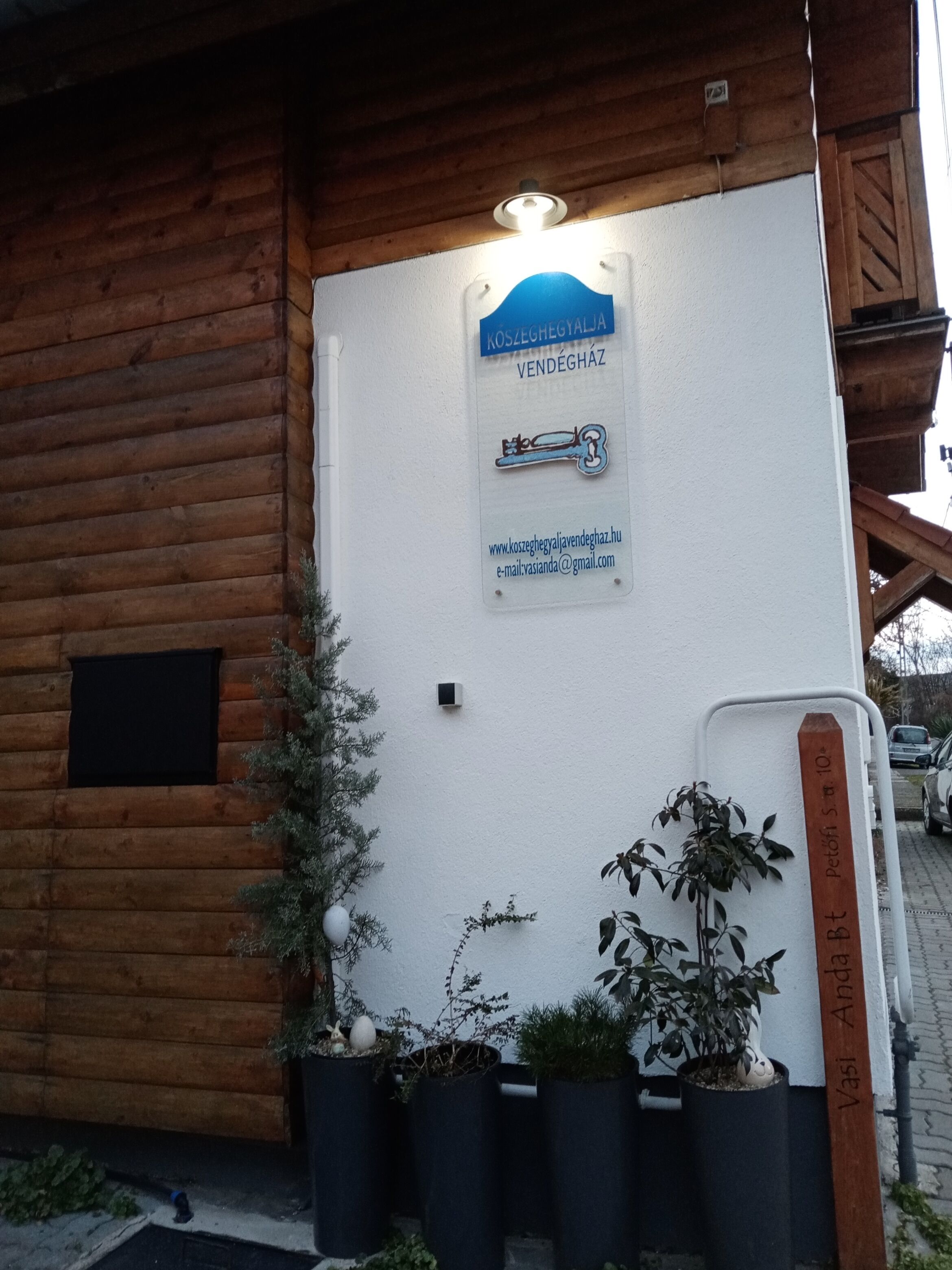A wooden building with a signboard displaying a key symbol and contact information.