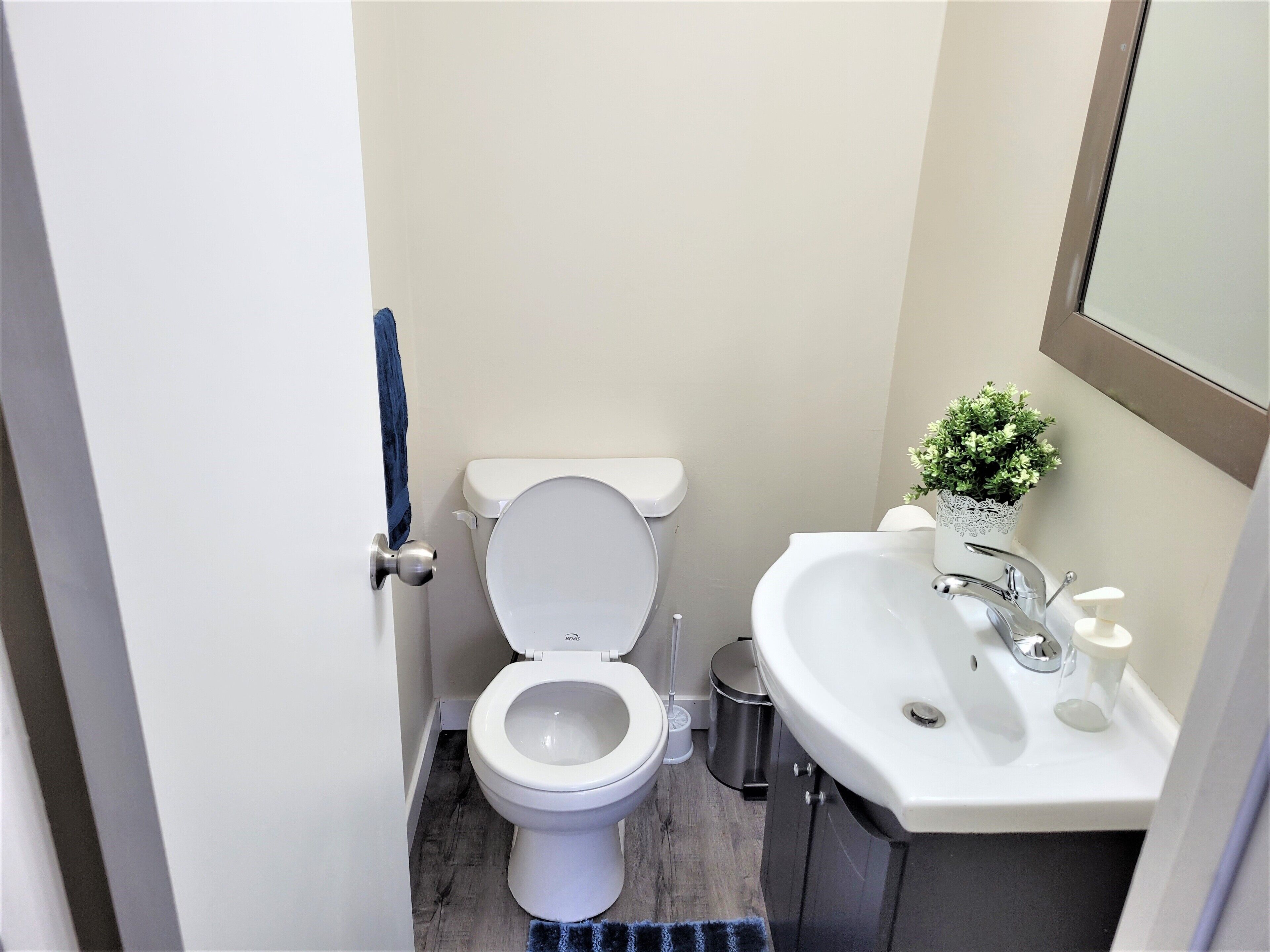 A compact bathroom with a toilet, sink, and a small potted plant.