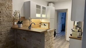 Een moderne keuken met witte kasten, een accentmuur van steen, en een potorkidee.