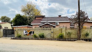 A residential area with a gated entrance, a house with a tiled roof, and a wall with a sign. - Abrama Bed And Breakfast (Francistown)