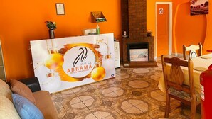 A hotel reception area with a reception desk, a fireplace, a dining table, and a chair. - Abrama Bed And Breakfast (Francistown)
