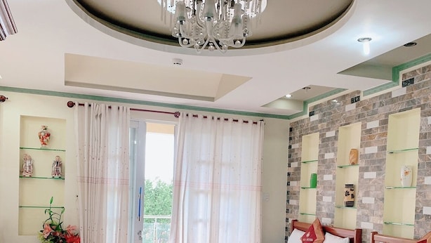 Una habitación de hotel con dos camas, un candelabro, un balcón con cortinas y estanterías decorativas.
