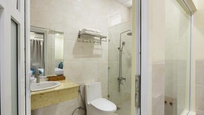 Un baño moderno con ducha envuelta en vidrio, inodoro blanco y tocador con espejo y lavamanos.