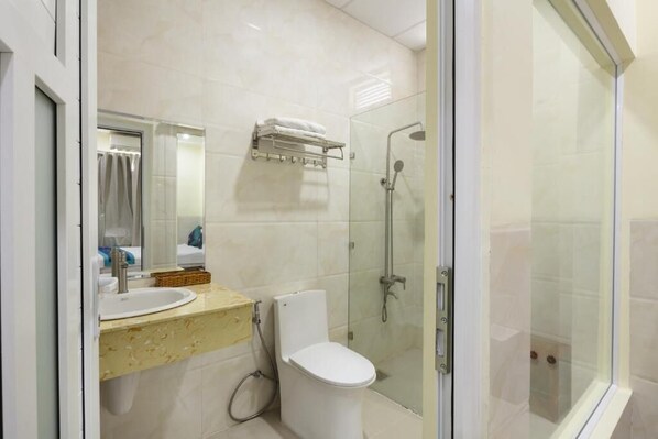 A modern bathroom with a glass-enclosed shower, a white toilet, and a vanity with a mirror and sink.