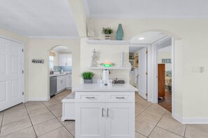 A kitchen with white cabinets, a coffee maker, and a plant on the countertop.