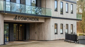 Un edificio moderno con un letrero que dice "deEGMONDEN" y un balcón de vidrio.
