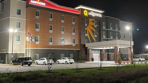 Ein mehrstöckiges Hotel mit 'Hawthorn'- und 'La Quinta'-Beschilderung, das ein modernes Design und ein markantes Sonnensymbol aufweist.