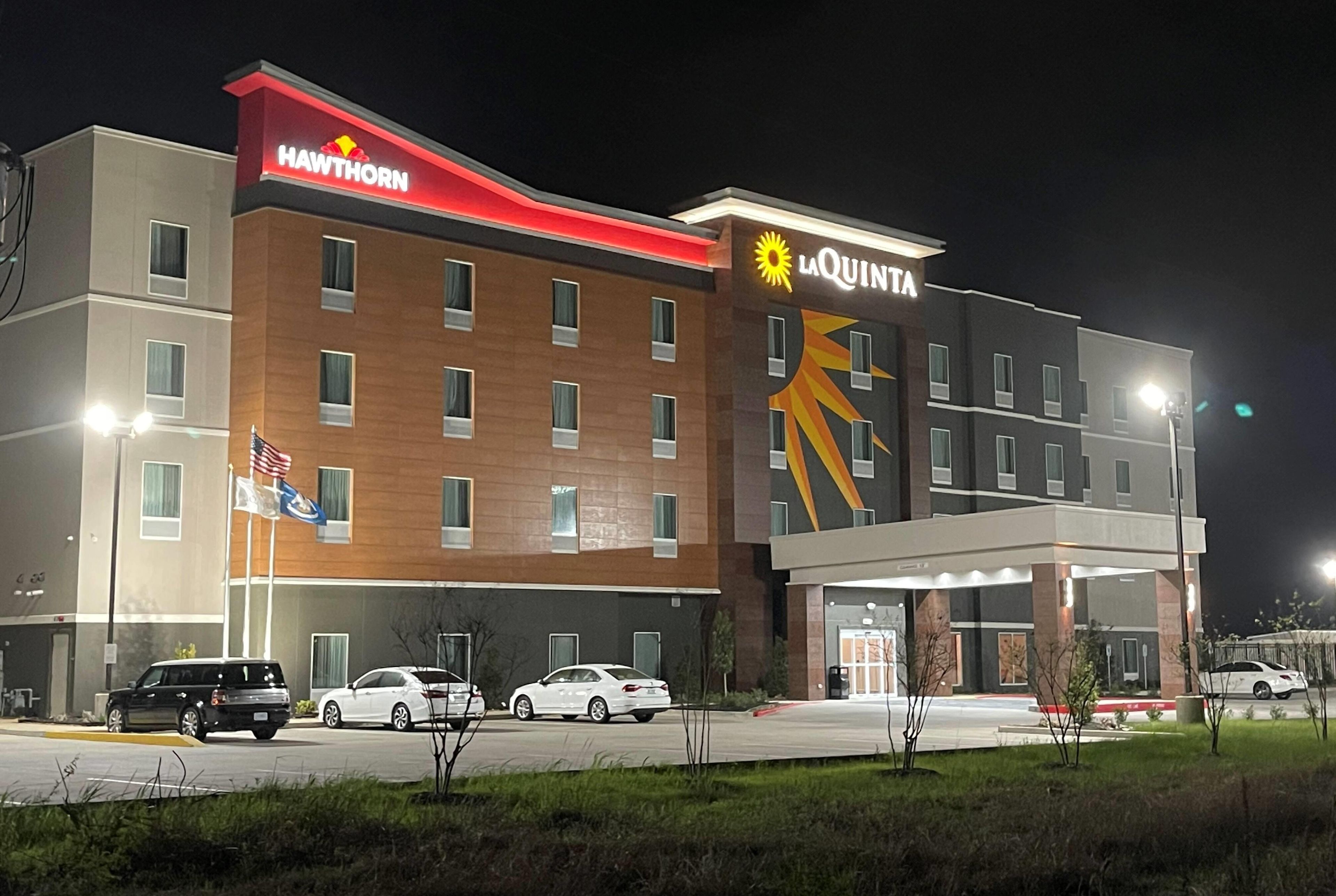 A multi-story hotel with a red awning labeled 'HAWTHORN' and a yellow awning labeled 'LA QUINTA'.