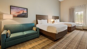 Ein Hotelzimmer mit einem großen Bett, einem kleineren Bett, einer Couch, einem Gemälde, einer Lampe und einem Fenster mit Vorhängen.