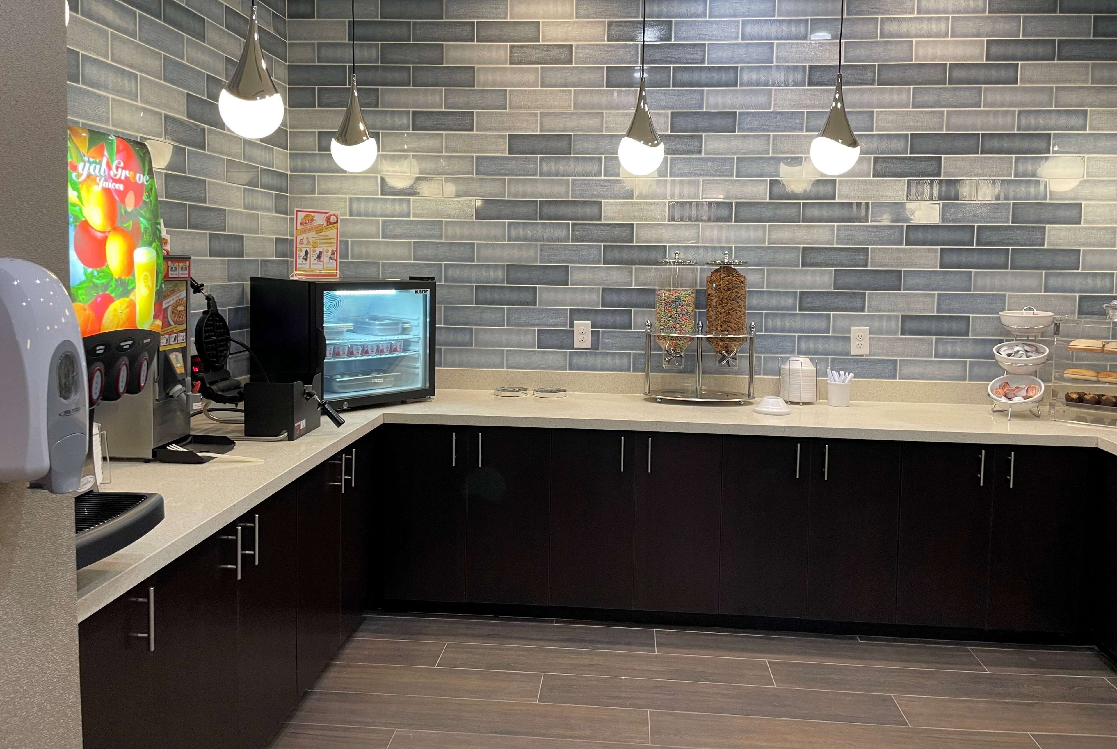 Una cocina moderna con salpicadero de ladrillo, una cafetera, una balanza digital y una vitrina de cristal.