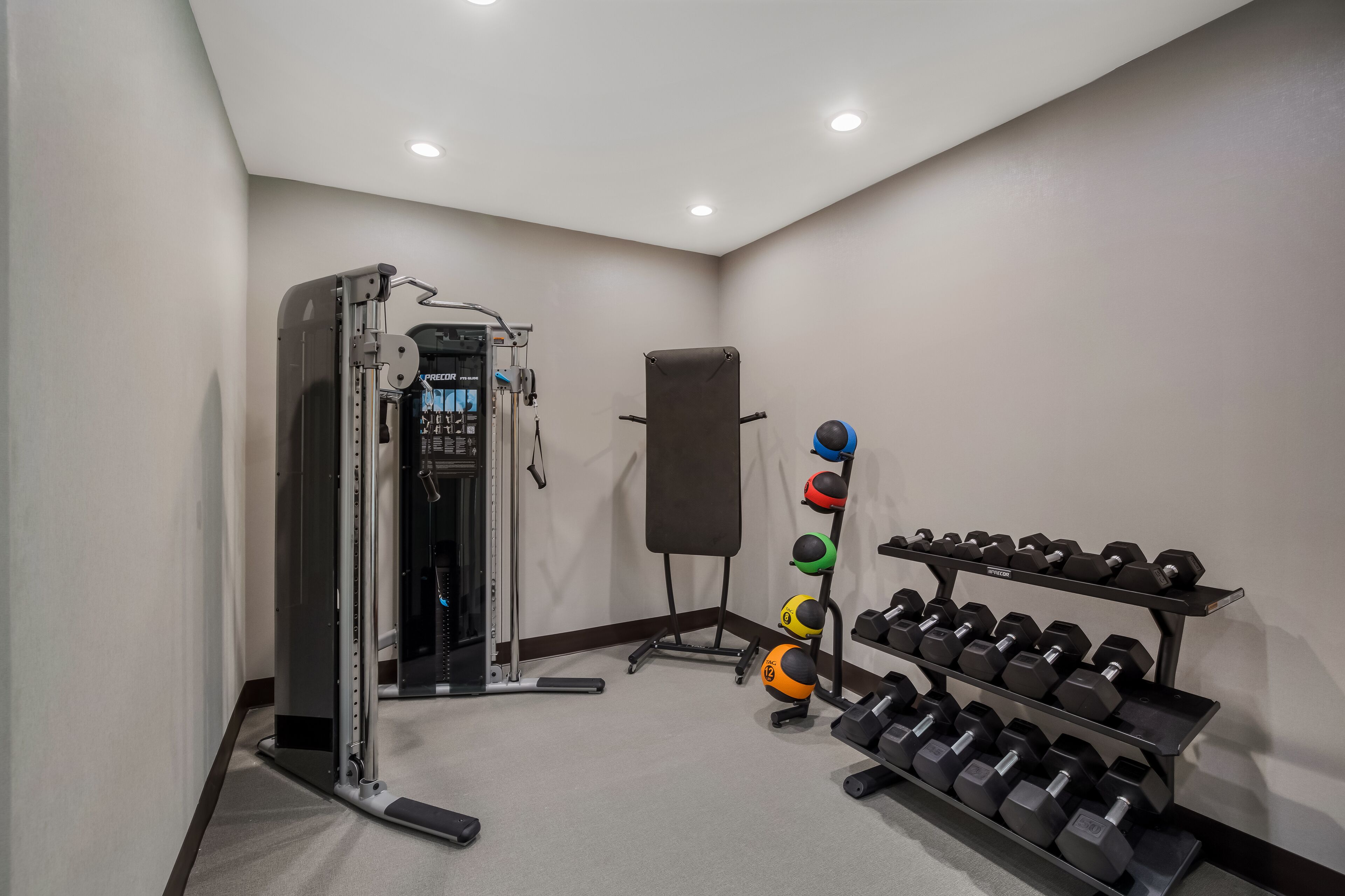 Une salle de sport équipée de matériel de musculation, notamment des haltères et un support à squats.
