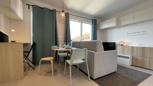 A modern living room with a sofa, chairs, a dining table, and a TV.