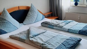 Un lit avec un cadre en bois, plusieurs oreillers et une couverture bleue à motifs.