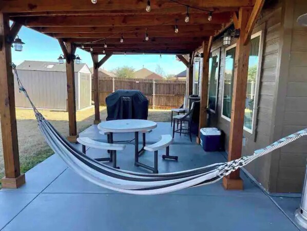 Relax in an outdoor space with a shaded pergola, round dining table, and hammock.