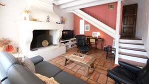 A living room with a fireplace, a sofa, a coffee table, and a staircase leading to another level. - Vacation rental house with pool MOULES LS3-424 (Arles)