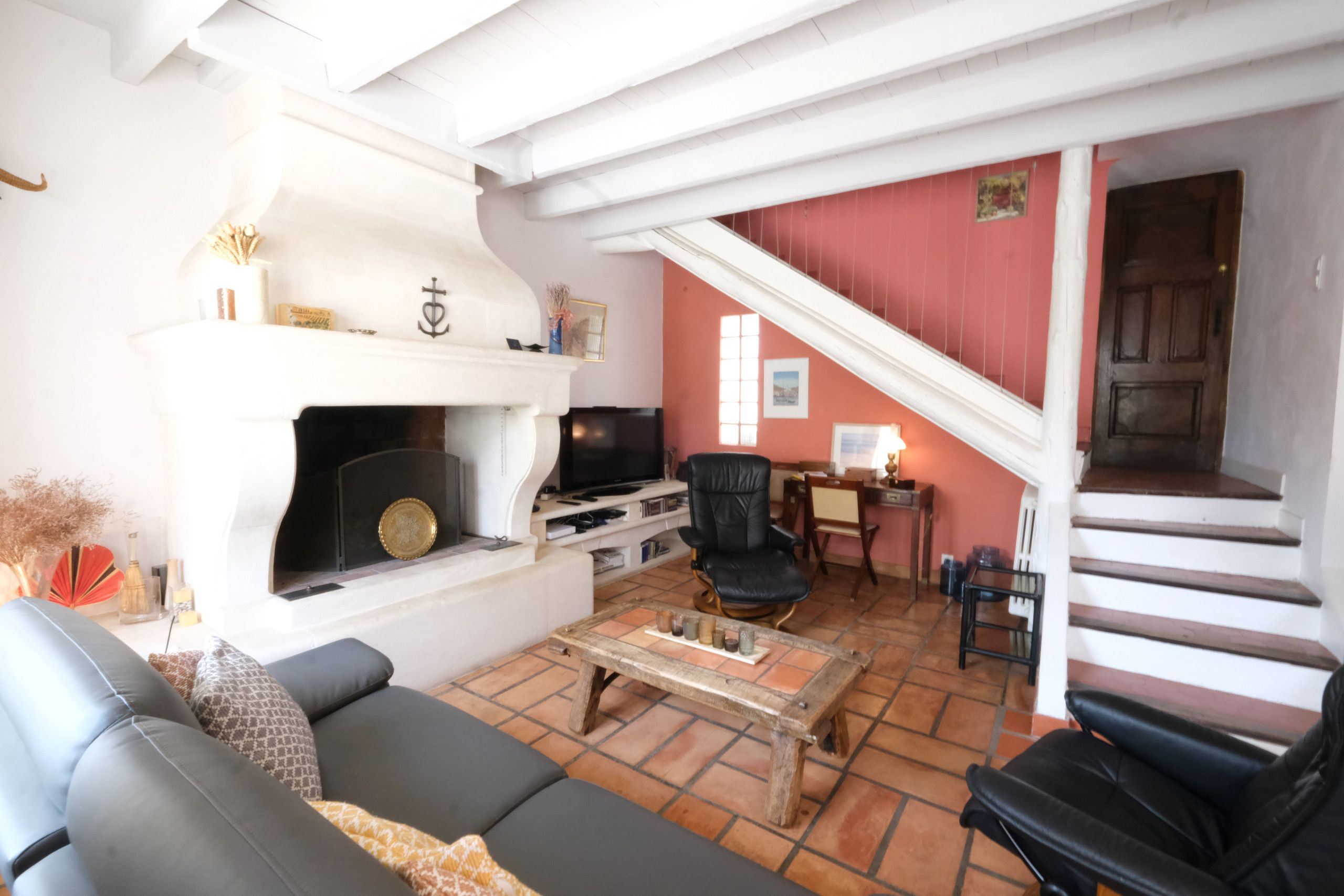 Un salon avec une cheminée, un canapé, une table basse et un escalier menant à un autre niveau.