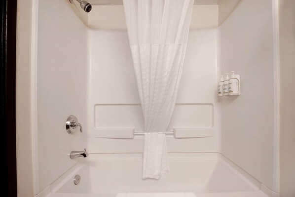 A white bathroom with a shower curtain, a towel rack, and a bottle of hand soap.