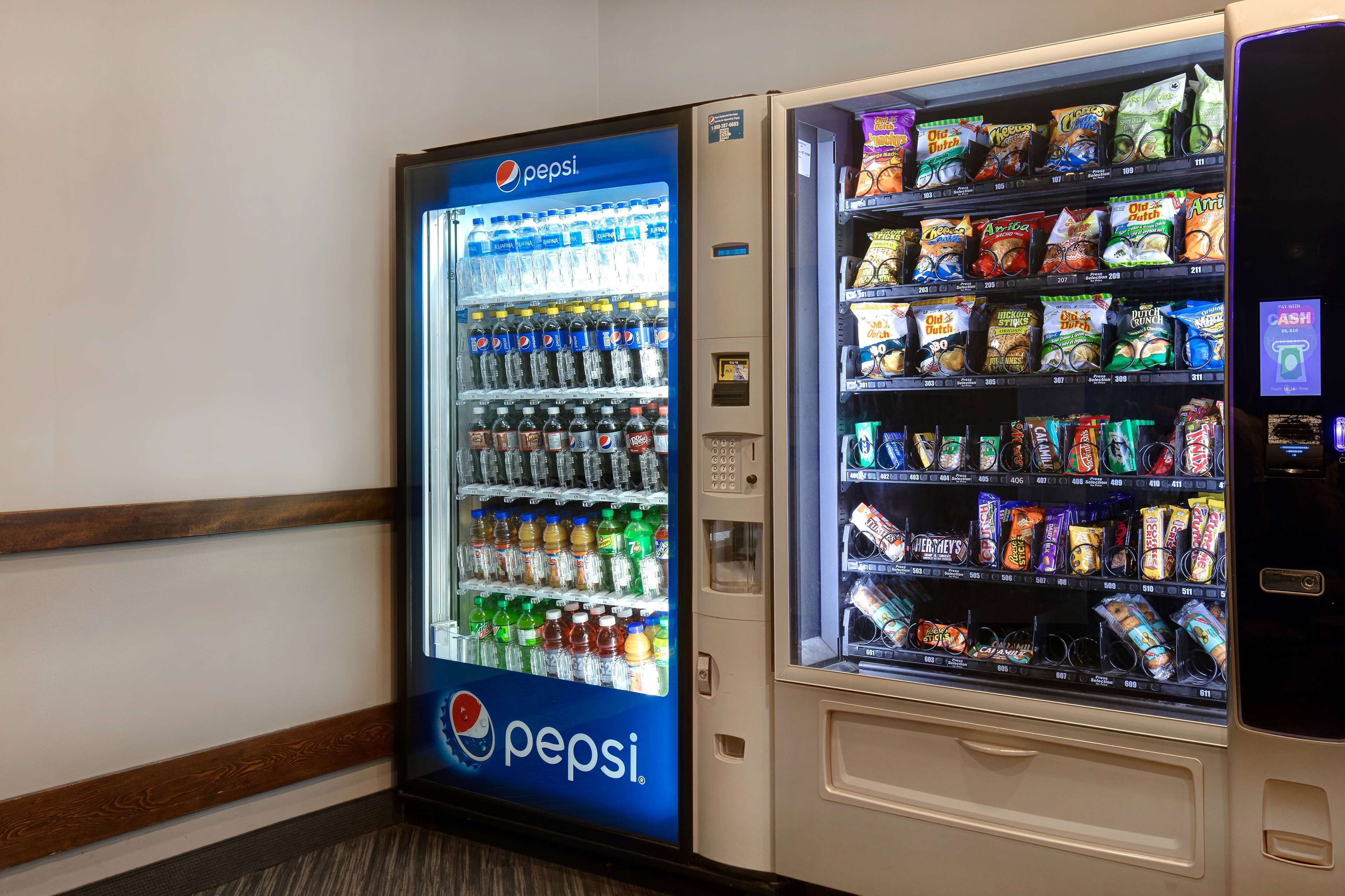 Un distributeur automatique arborant le logo Pepsi, avec un autre distributeur, cette fois pour les en-cas, placé à côté.