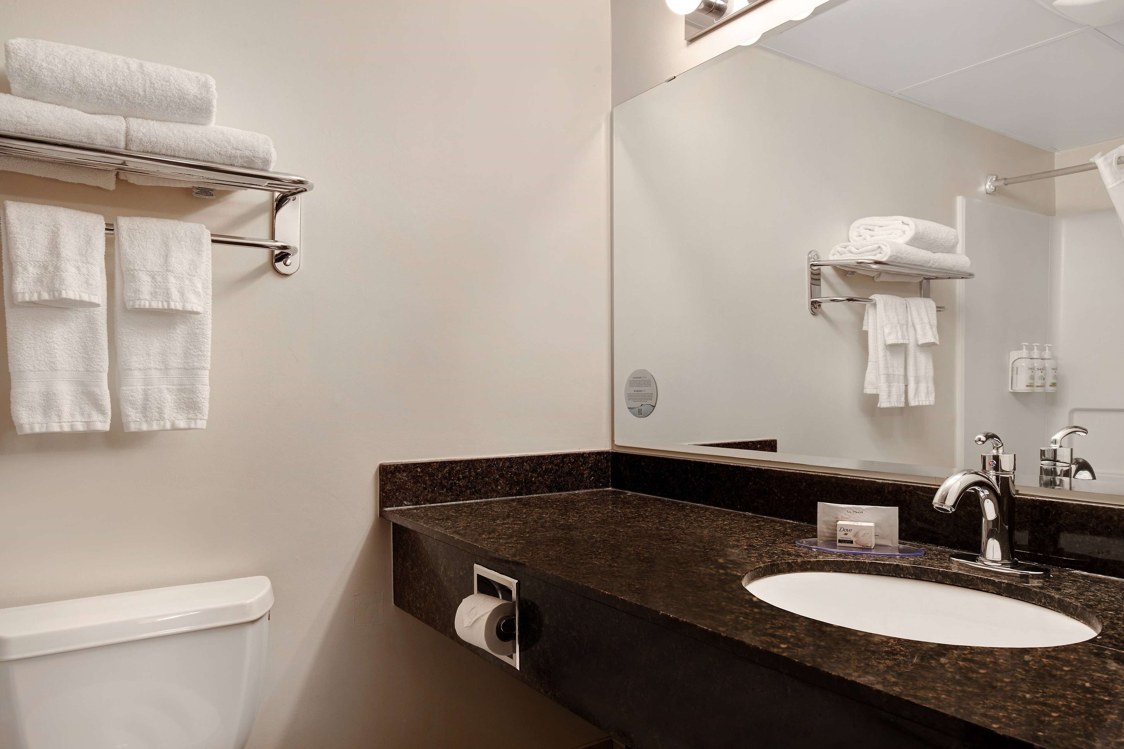 A modern bathroom with a sink, mirror, towel rack, and toilet.