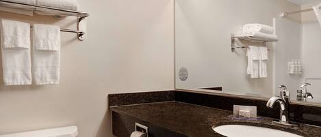 A modern bathroom with a sink, mirror, towel rack, and toilet.