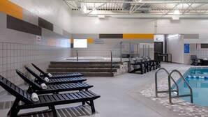 Un espace piscine comprenant des chaises longues, un jacuzzi et un escalier menant à un vestiaire.