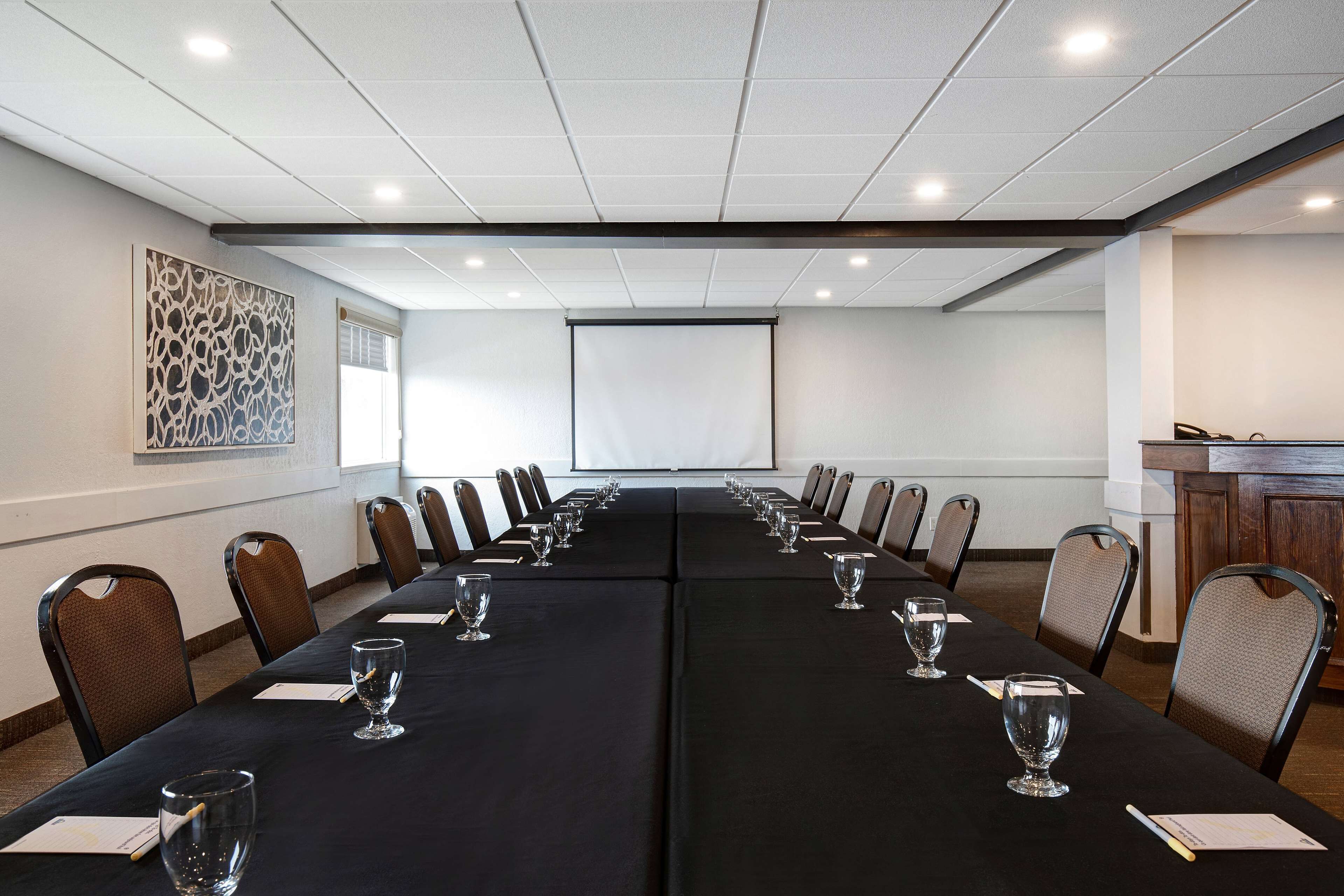 Une salle de conférence équipée d’une longue table, de chaises et d’un écran de projection.