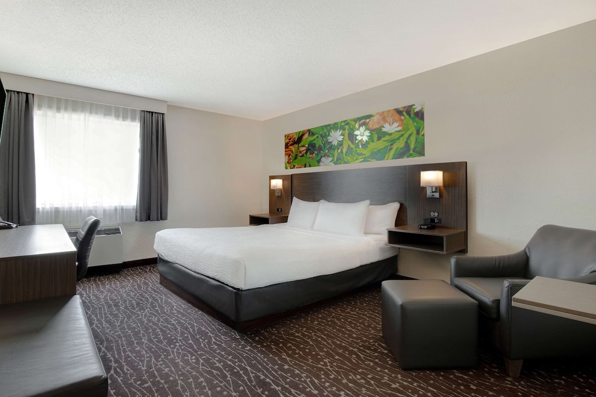 Ein Hotelzimmer mit einem großen Bett, einem Schreibtisch, einem Sessel und einer Couch.