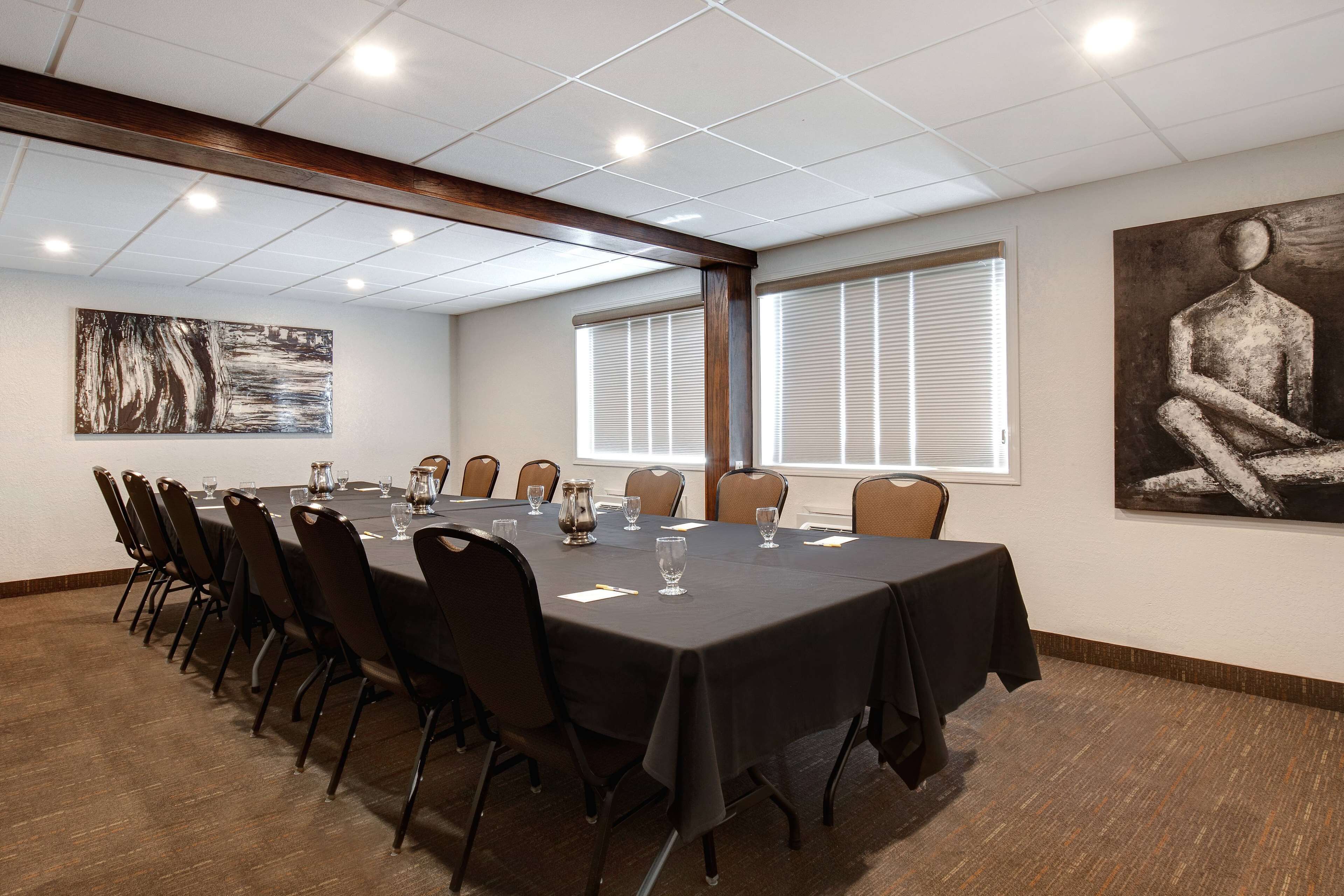 Une salle de conférence avec une longue table, des chaises et des œuvres d’art accrochées aux murs.