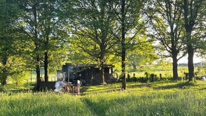 Una cabaña rústica en un campo cubierto de hierba, rodeada de árboles.
