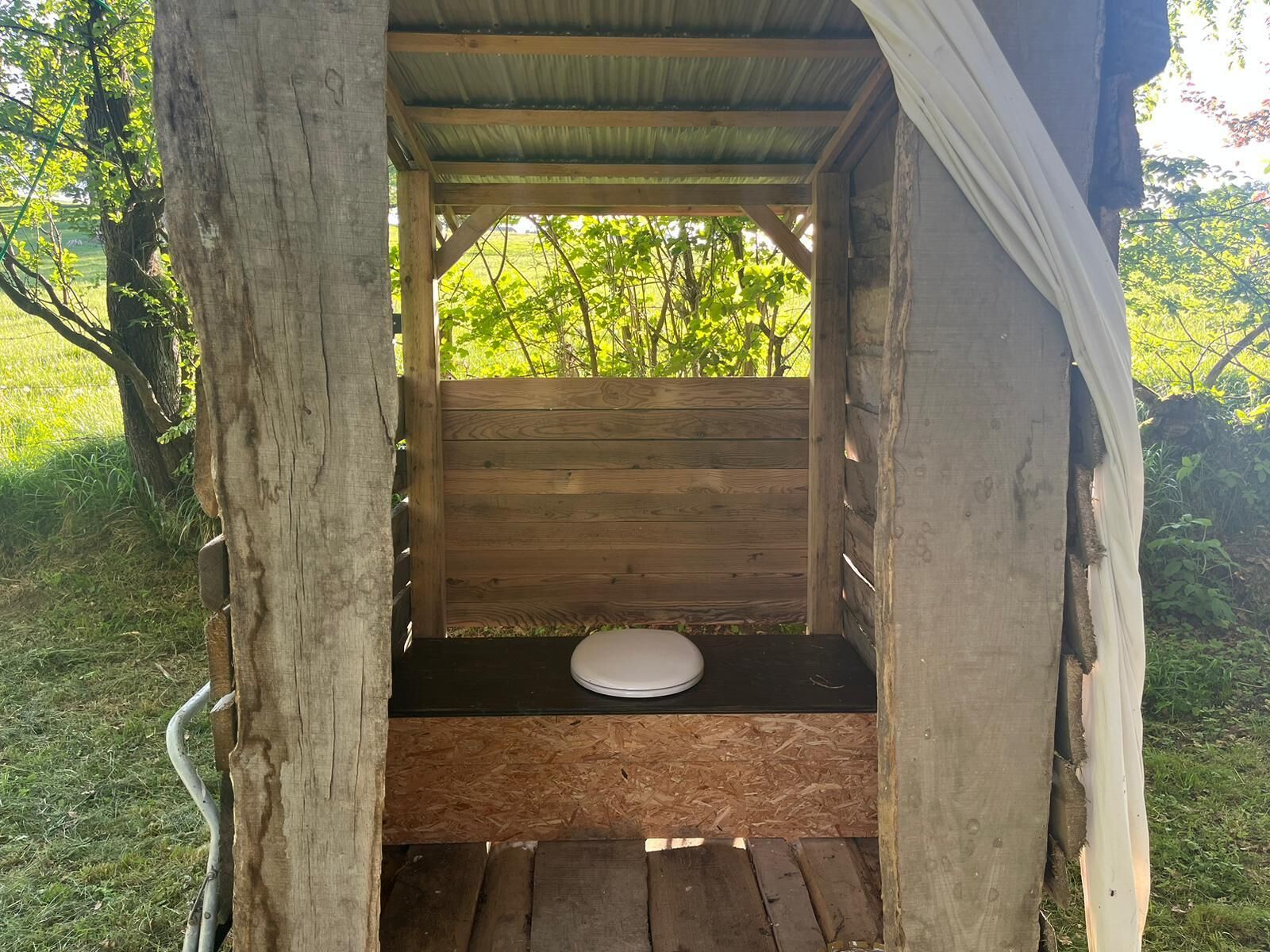 A wooden structure with a bench and a toilet inside.