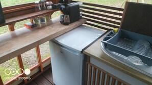 Una cocina compacta con refrigerador, cafetera y escurreplatos.