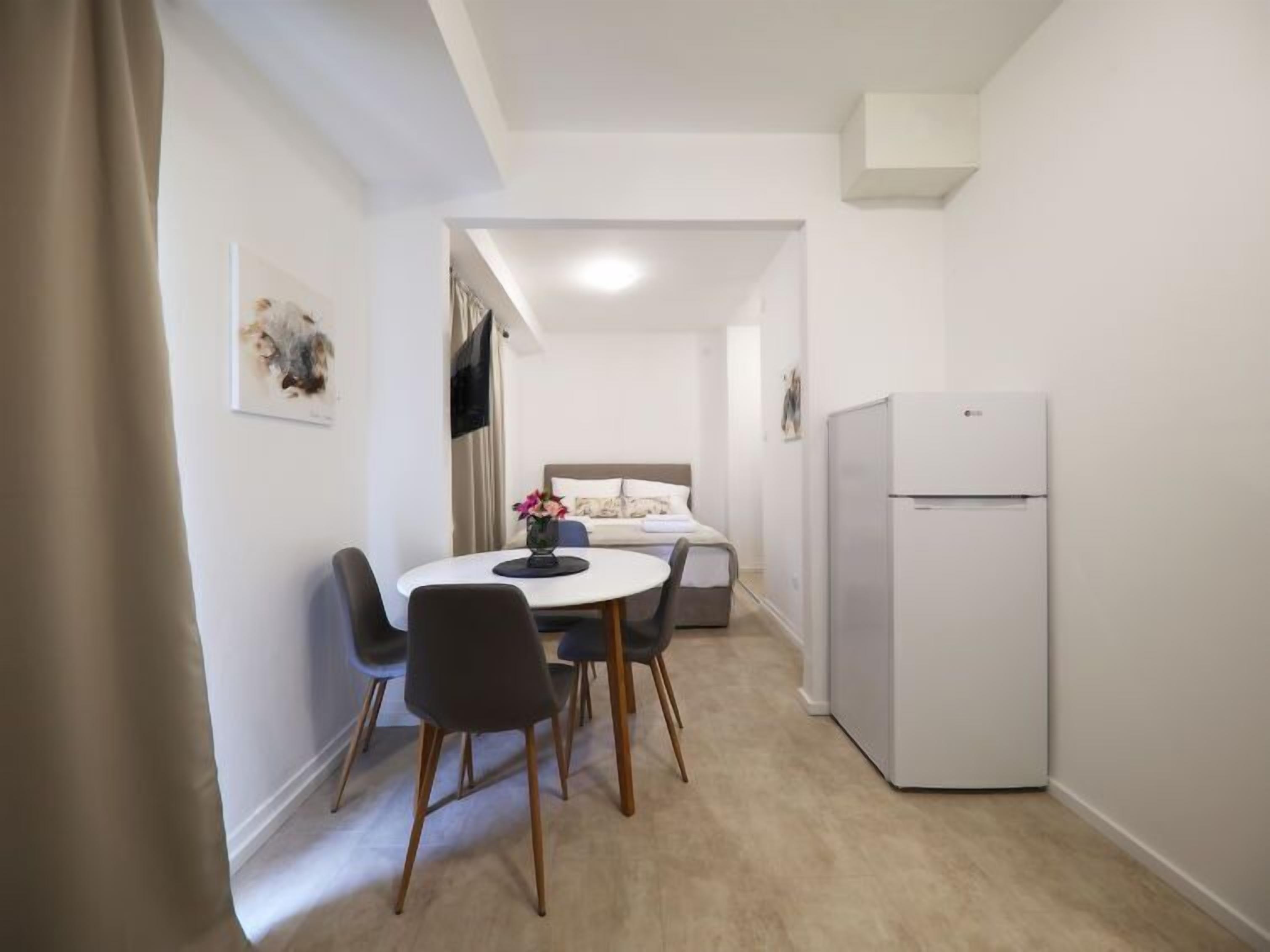 A compact living space with a dining area, a bed, and a refrigerator.