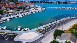 Un port de plaisance avec des bateaux amarrés, un parking et une ville en arrière-plan.