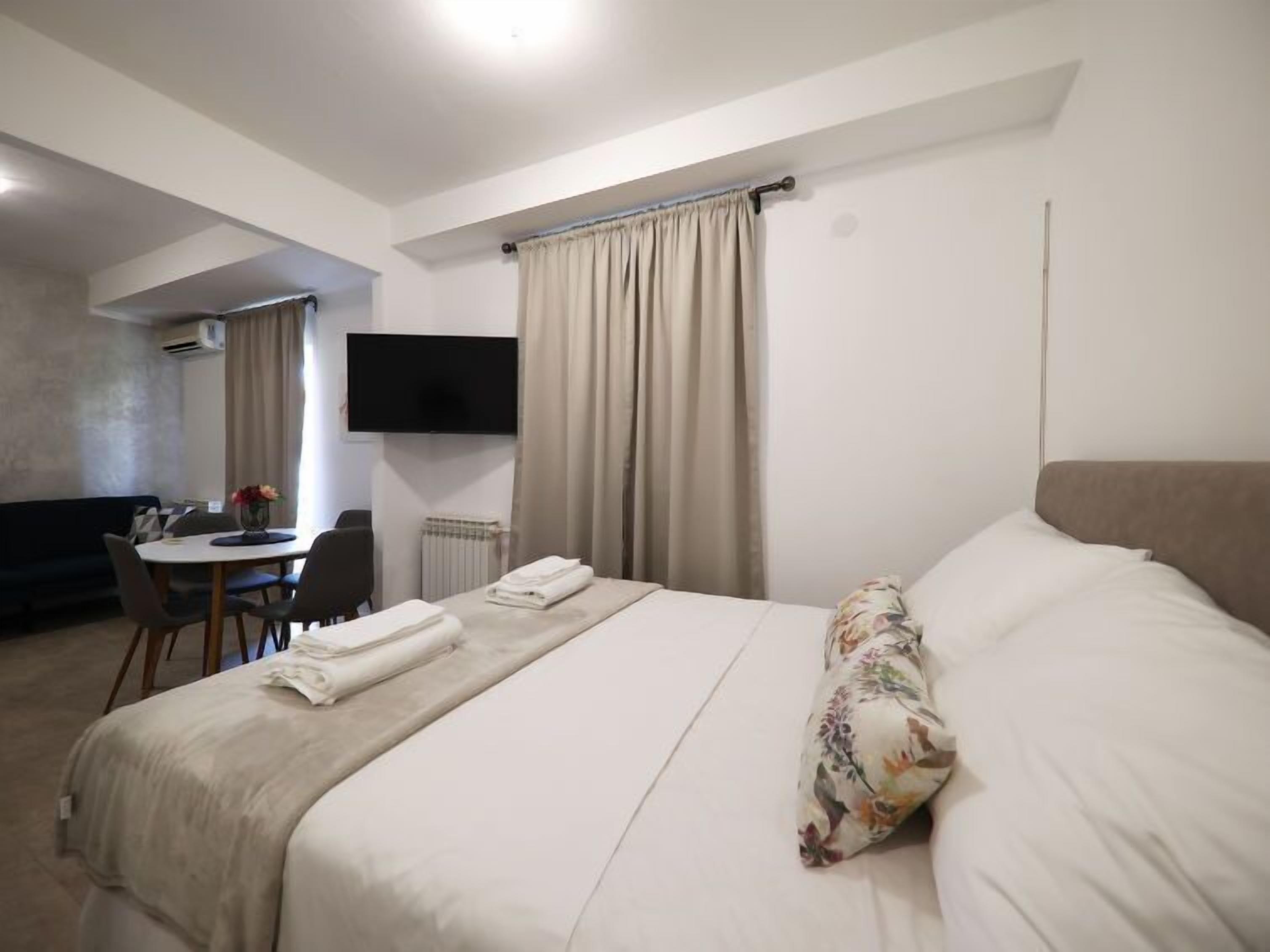 Une chambre d’hôtel équipée d’un lit, d’un bureau, d’une chaise, d’une télévision et d’une fenêtre avec des rideaux.