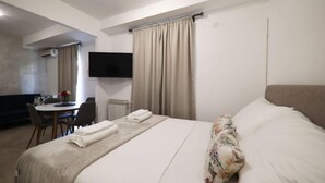 Une chambre d’hôtel équipée d’un lit, d’un bureau, d’une chaise, d’une télévision et d’une fenêtre avec des rideaux.