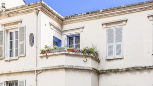 A corner building with white walls, blue shutters, and a small balcony with potted plants. - Apartment Hérold by Interhome (Nice)
