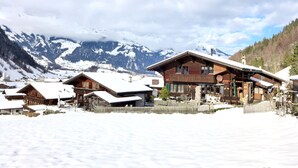 A wooden chalet with a balcony, surrounded by snow-covered houses and mountains in the background. - Elsighornblick by Interhome (Kandergrund)