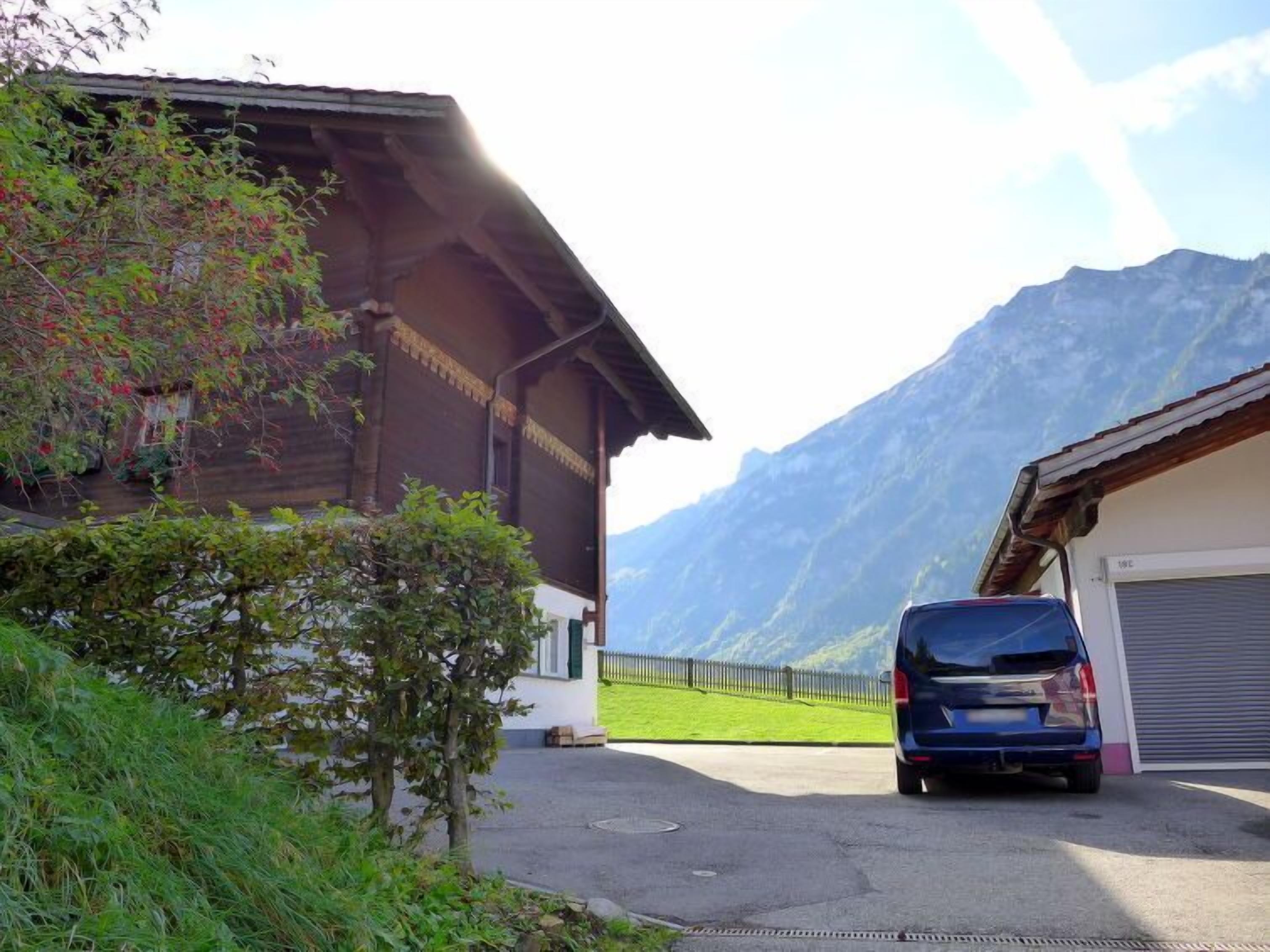 Un edificio con un garage, un'auto parcheggiata e montagne sullo sfondo.