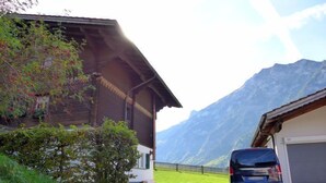 A building with a garage, a parked car, and mountains in the background. - Elsighornblick by Interhome (Kandergrund)