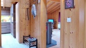 A wooden interior with a kitchen area, a seating area with a TV, and a shoe rack. - Elsighornblick by Interhome (Kandergrund)