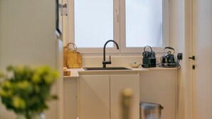 A compact kitchen with a sink, kettle, and a small countertop.
