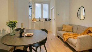 A modern living room with a round dining table, a sofa, and a large window.