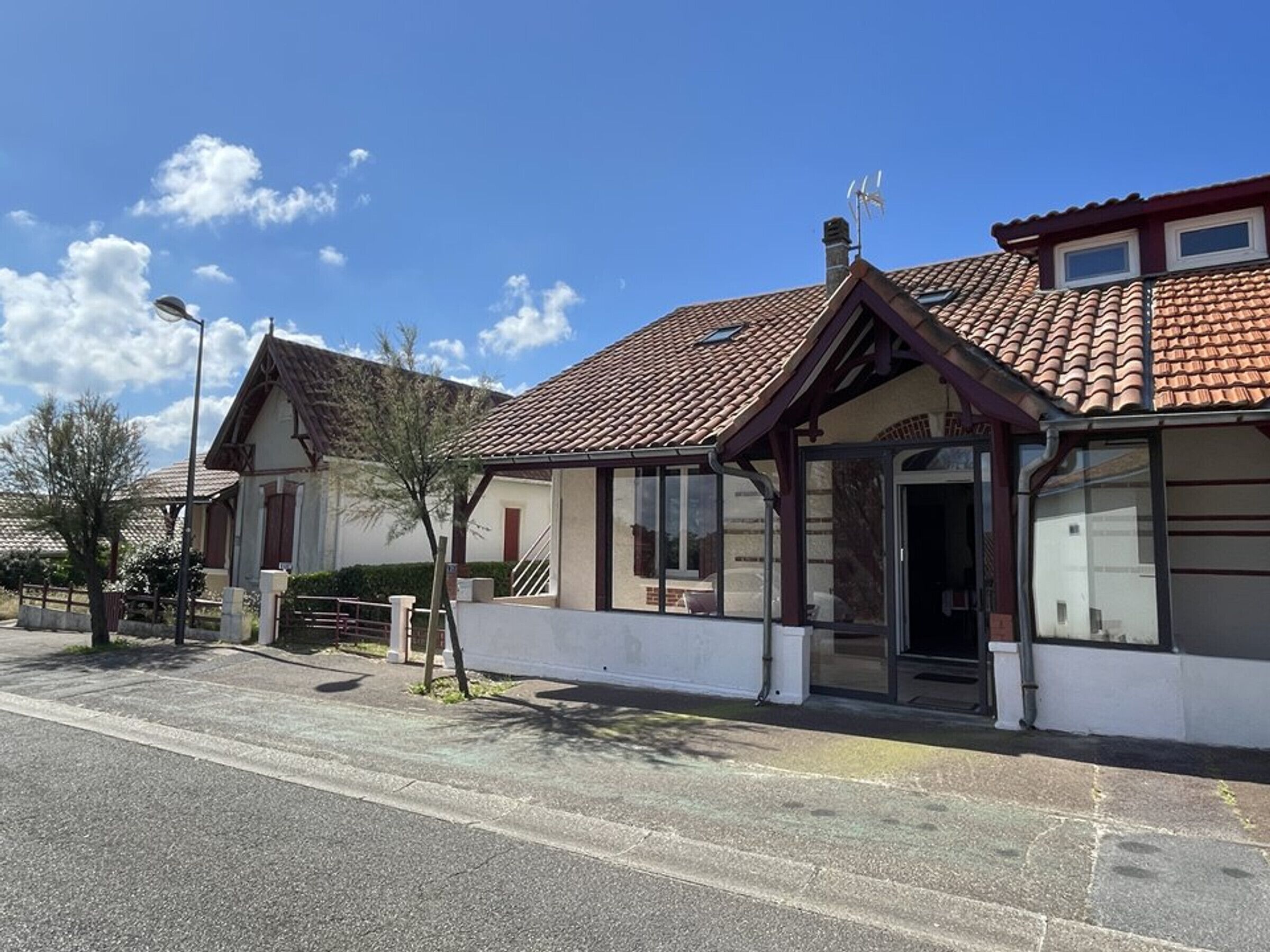 En tvåvåningsbyggnad med ett tak täckt av takpannor, en inglasad veranda och en tydligt markerad entré.
