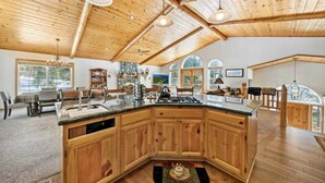 Una cocina amplia con una isla grande, techo de madera y ventanas panorámicas.